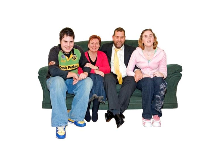 Four people sitting on a green sofa, smiling.
