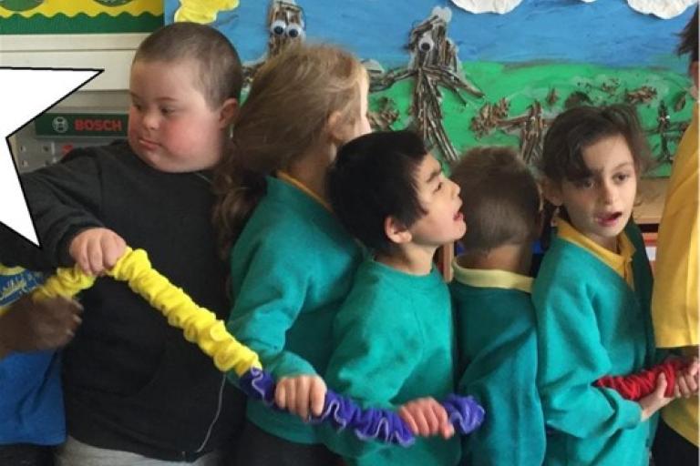 A group of children standing close together holding a colourful scrunchy tube.
