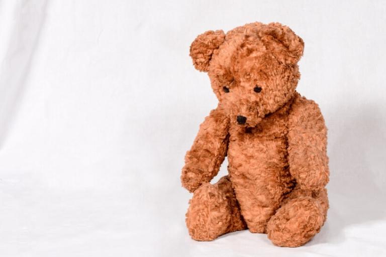 A teddy bear with its head bowed making it look sad
