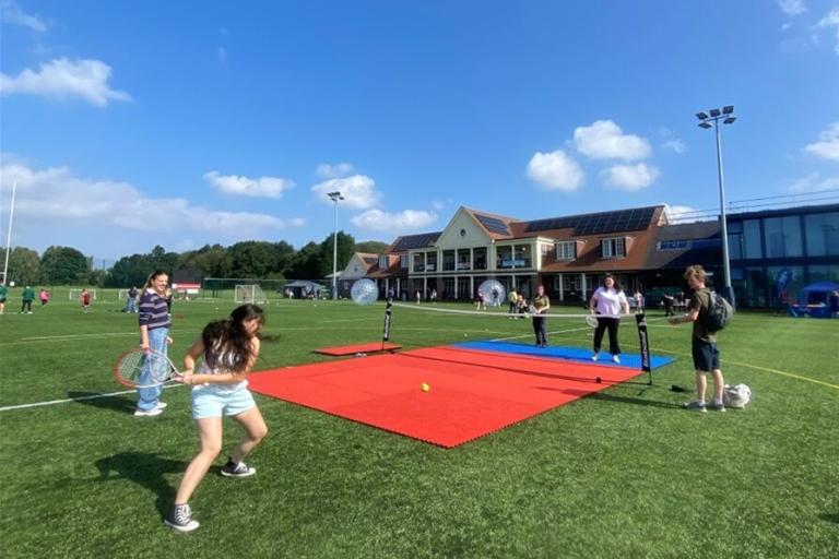 Group of young people playing tennis on a sunny day