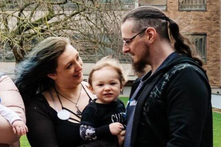 Young parents standing outside holding their babies and smiling