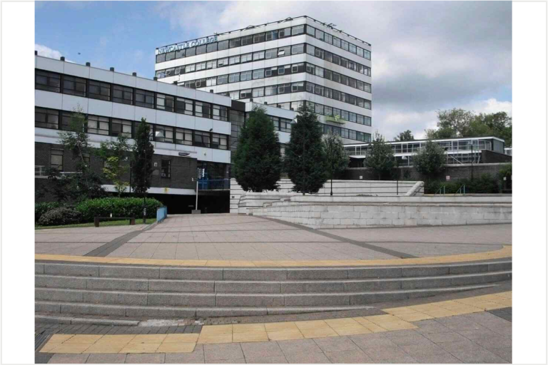 A tall Newcastle College building with a large paved area in front. 