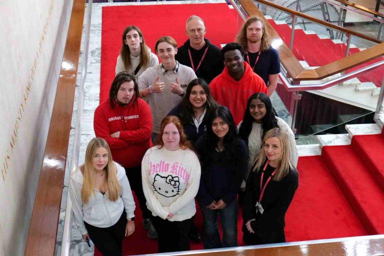 A group of young people standing on a red carpeted staircase