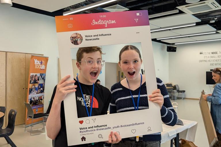 12112025Two young people behind a selfie frame 