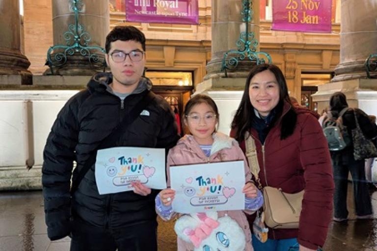 Young people holding a 'thank you for 100k of free tickets' outside Newcastle Theatre Royal