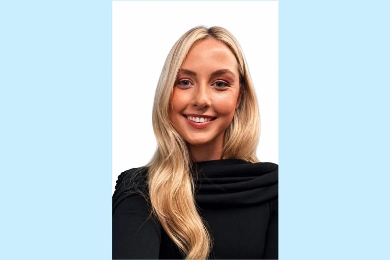 Close up of Kate smiling in front of a white background. 