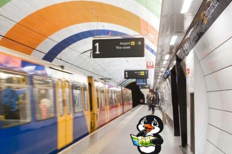 A metro platform with a metro carriage going past. A cartoon penguin with a map is standing on the platform. 