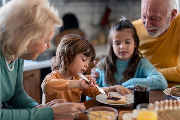 Grandparents sat at table with two grandchildren. 