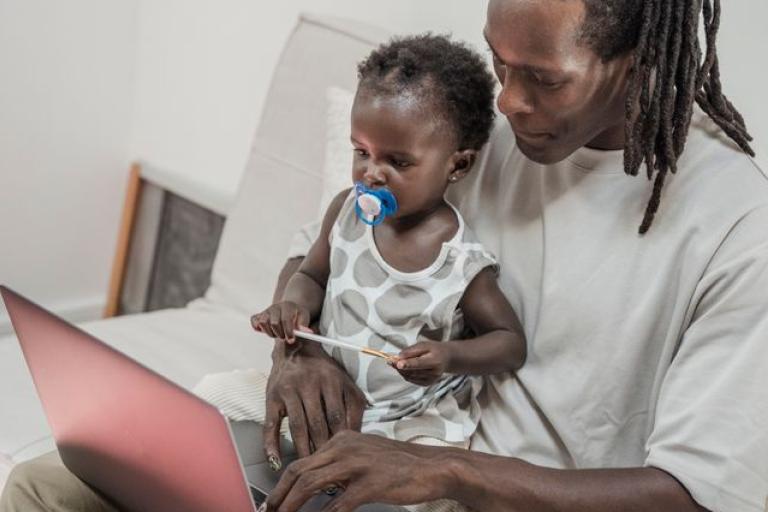Parent on laptop with baby on lap 