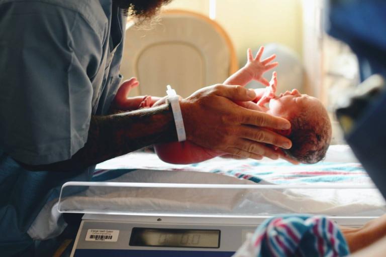 Midwife weighing baby