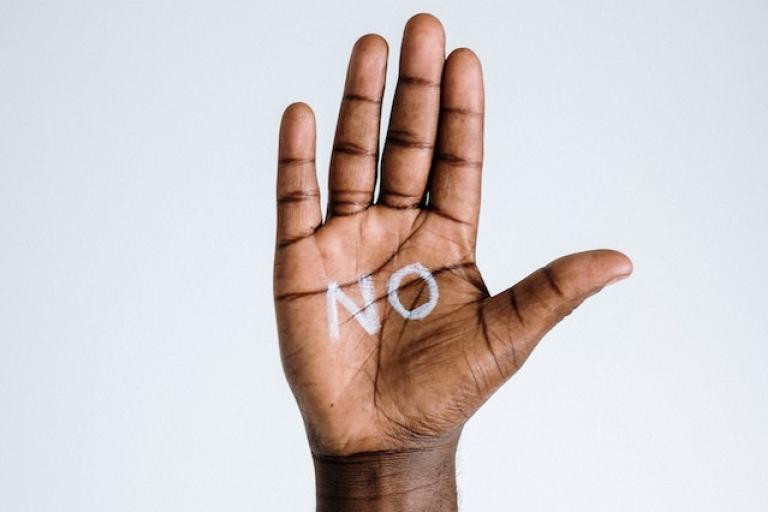 A raised hand with the word 'no' written on the open palm