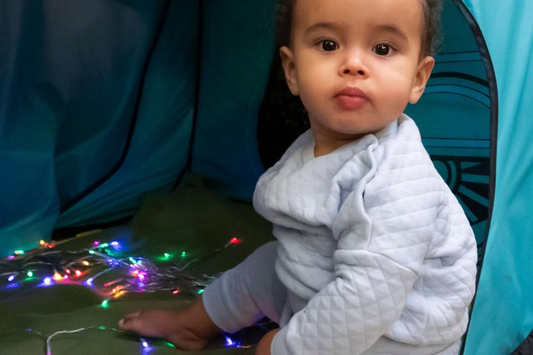 Baby sitting in an play tent with sensory lights 